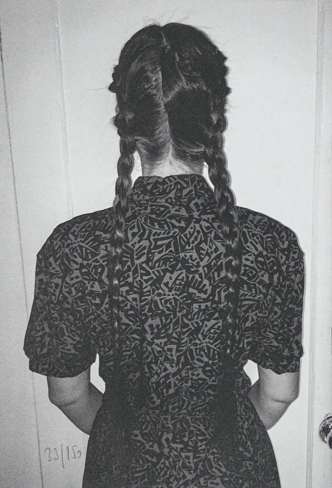 Image, taken from behind, of a person in a dress with two long braids.