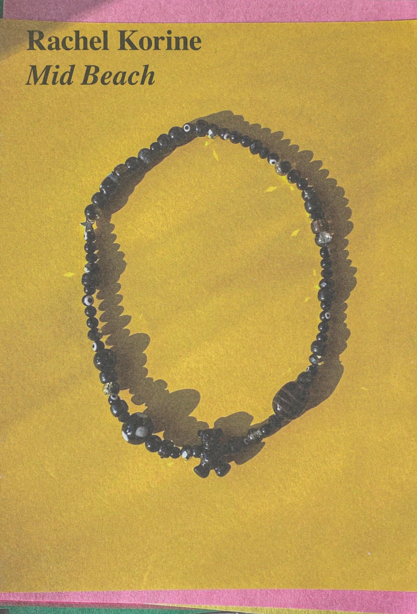 Book cover with the title and author in the upper left corner, above a photo of a beaded necklace on a yellow background outlined in pink.