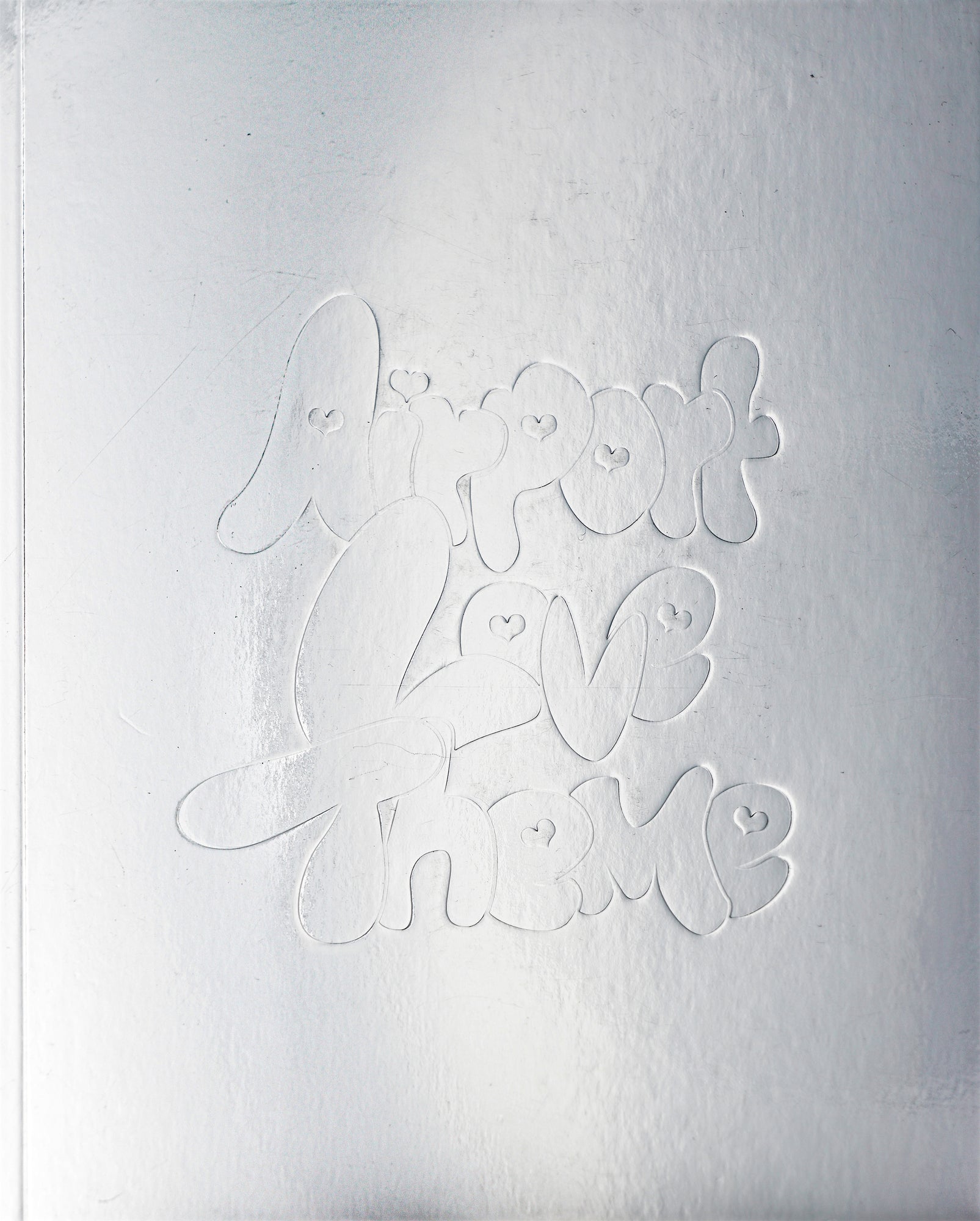 Silver cover with embossed, rounded custom type letters, spelling out the title 'Airport Love Theme'. The typographical counters are replaced by little hearts.