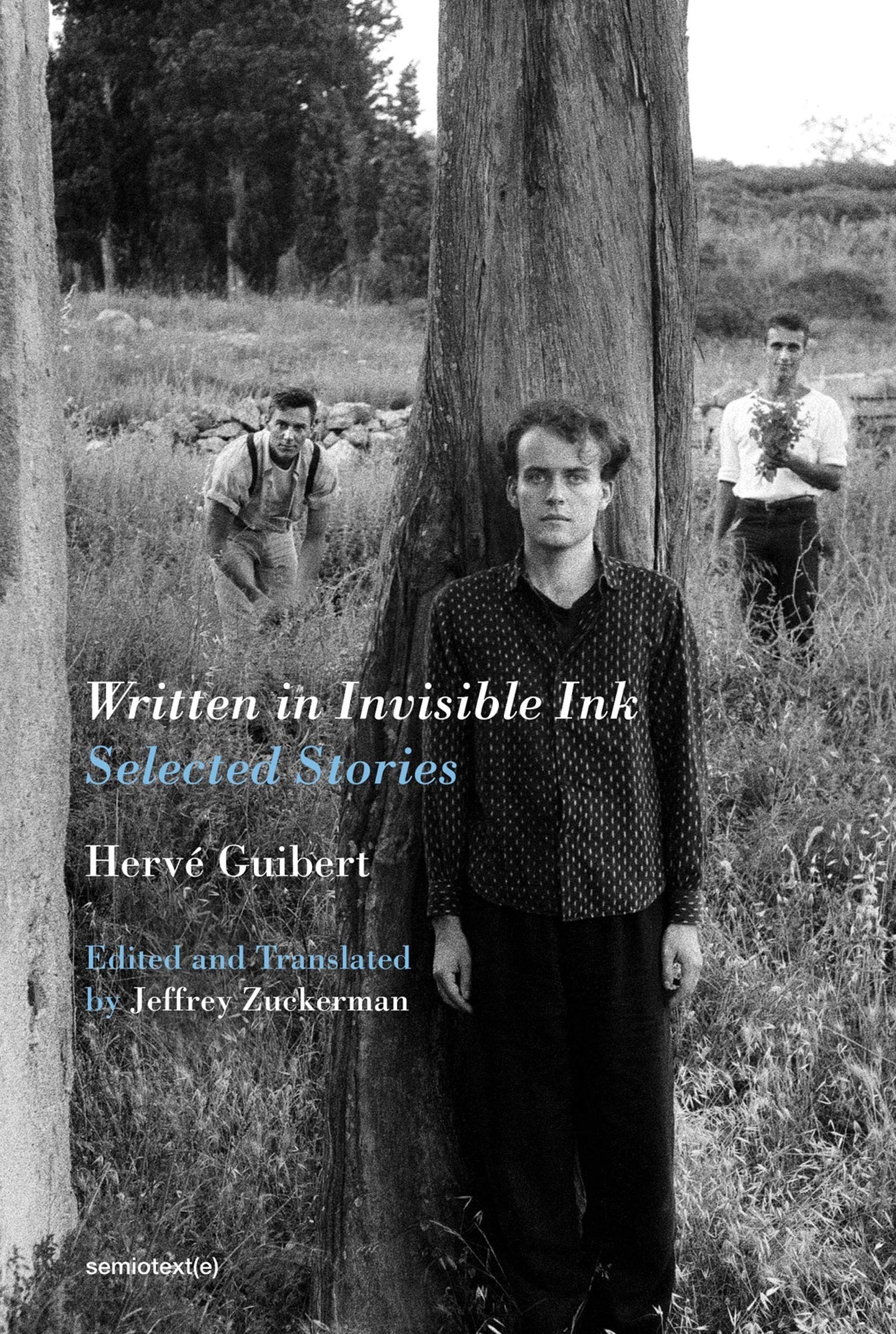  Written in Invisible Ink Selected Stories Hervé Guibert Editied and Translated by Jeffrey Zuckerman in serif white and light blue type with an image of the auhtor standing against a tree and two other men in the backgroud