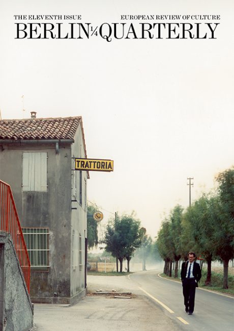 Photo of a rural town, a Trattoria set on a single-lane country road, lined on both sides by short, bushy trees. A man stands in the middle of the road, walking towards the camera. On the top of the cover, the title is written: Berlin Quarterly: The Eleventh Issue European Review of Culture